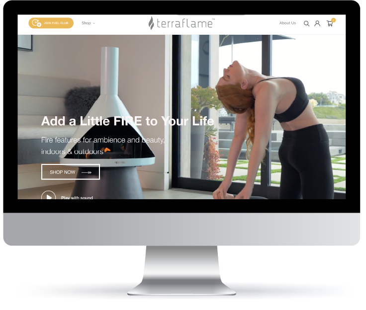 Woman stretching indoors near a modern decorative fireplace with a laptop displaying a TerraFlame e-commerce website.