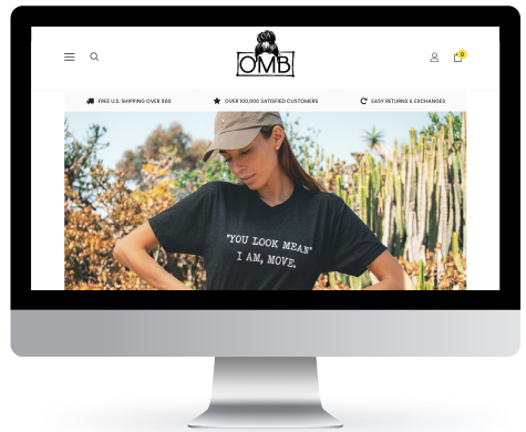Woman wearing a black t-shirt with text standing in a field with cacti in the background on the OMB brand website homepage.