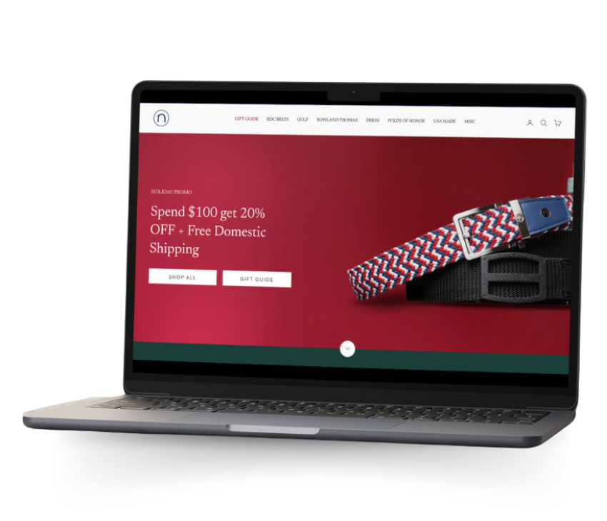 Laptop displaying a holiday promotional banner for an e-commerce website advertising 20% off and free domestic shipping with a red leather belt product image.